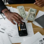 Dokumen keuangan dengan kalkulator dan laptop untuk perencanaan investasi